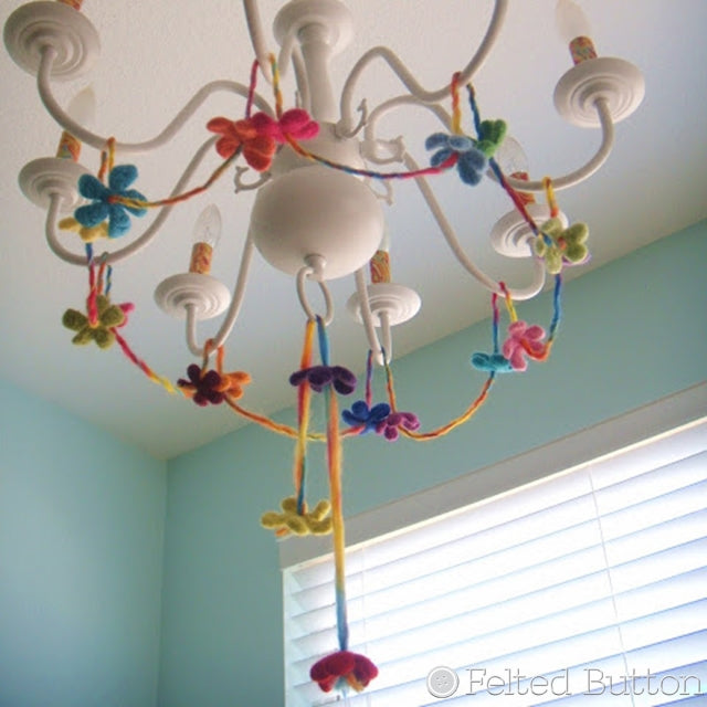 Wee Felted Blossoms on string hanging from white chandelier, Susan Carlson of Felted Button | Colorful Crochet Patterns