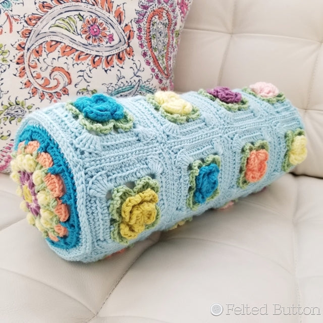 Primrose Pillow crochet pattern, blue pillow with blue, yellow, pink and orange textured flowers, crochet pattern by Susan Carlson of Felted Button colorful crochet patterns 