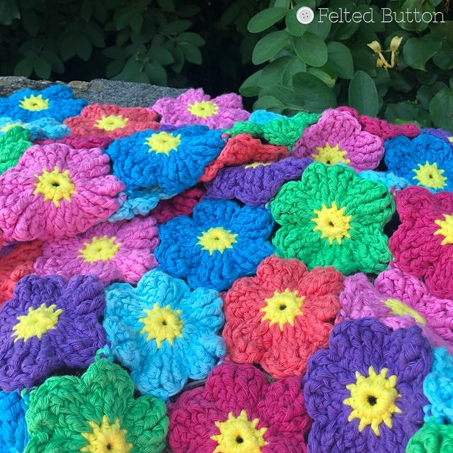 Rainbow if brightly colored crochet flowers blanket with yellow centers, Waikiki Wildflower Blanket crochet pattern made with Scheepjes Cahlista, by Susan Carlson of Felted Button colorful crochet patterns 