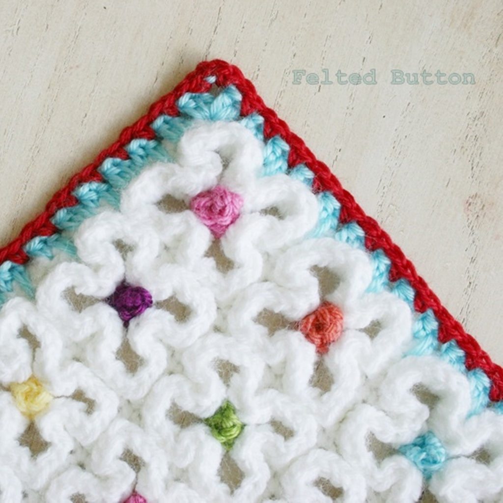 Wavy, textured crochet mat or blanket with colorful flower bud centers and red, turquoise border, designed by Susan Carlson of Felted Button