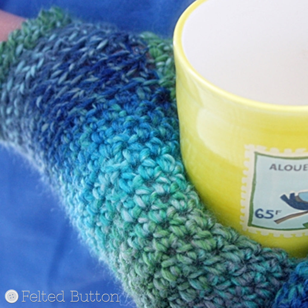 Blue and green mittens with hands holding mug, Sea Ice Mittens crochet glove pattern by Susan Carlson of Felted Button