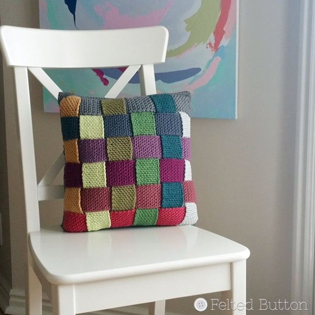 Crisscross Catona Cushion Cover, free crochet pattern; woven multi-colored pillow cover made in cotton, resting on white chair, by Susan Carlson | Felted Button | Colorful Crochet Patterns