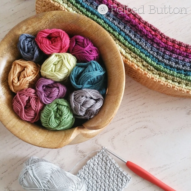 Scheepjes Catona cotton yarn in yarn bowl with jewel-toned colors and crochet hook for Crisscross Cushion Cover crochet pattern by Susan Carlson | Felted Button | Colorful Crochet Patterns