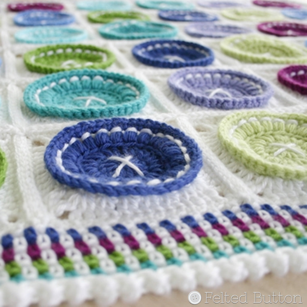 Bright as a Button Blanket crochet pattern by Susan Carlson of Felted Button, blue and green buttons on white background, colorful crochet 