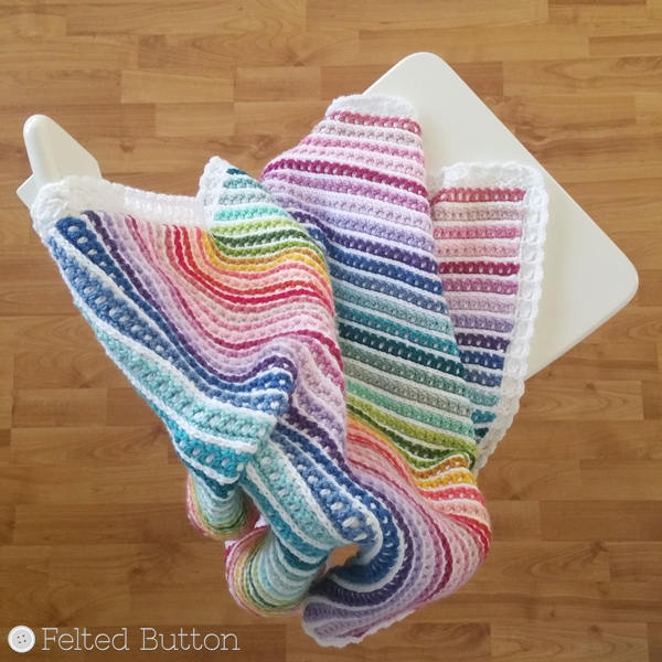 Rainbow striped and textured crochet blanket with white border and different texture on front and back, Janus Blanket by Susan Carlson of Felted Button, colorful crochet patterns