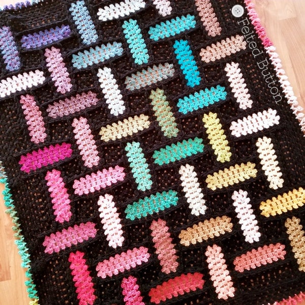 Rainbow of crochet granny rectangles that look like they are woven against a black background with pom edging, Warp and Weft free crochet patter by Susan Carlson of Felted Button