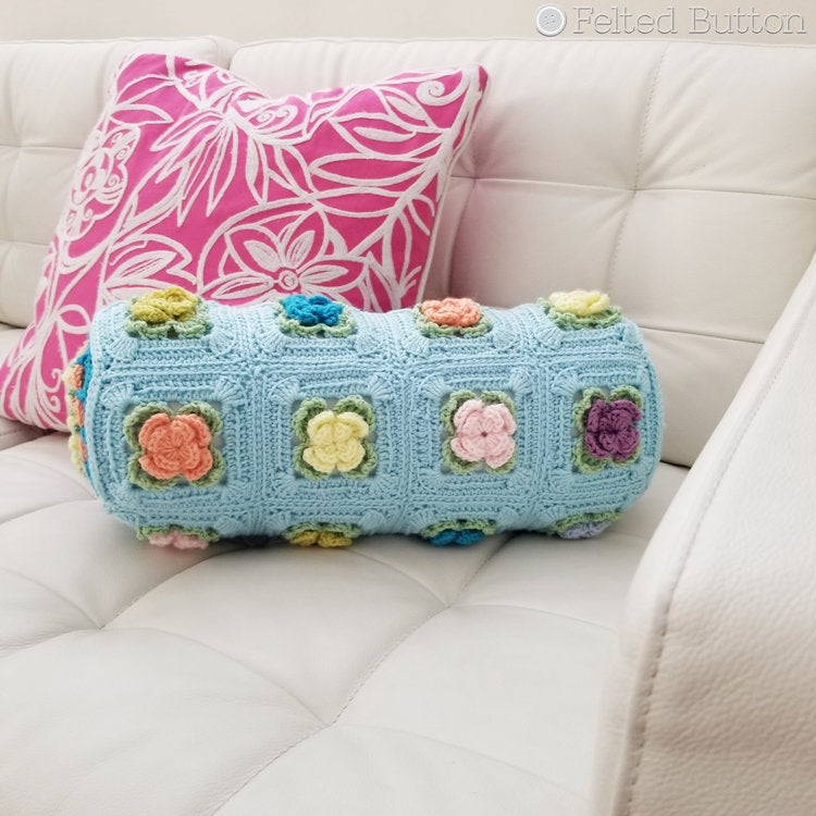Highly textured, blue and floral crochet cover over bolster pillow with mandala ends, Primrose Pillow crochet pattern by Susan Carlson of Felted Button